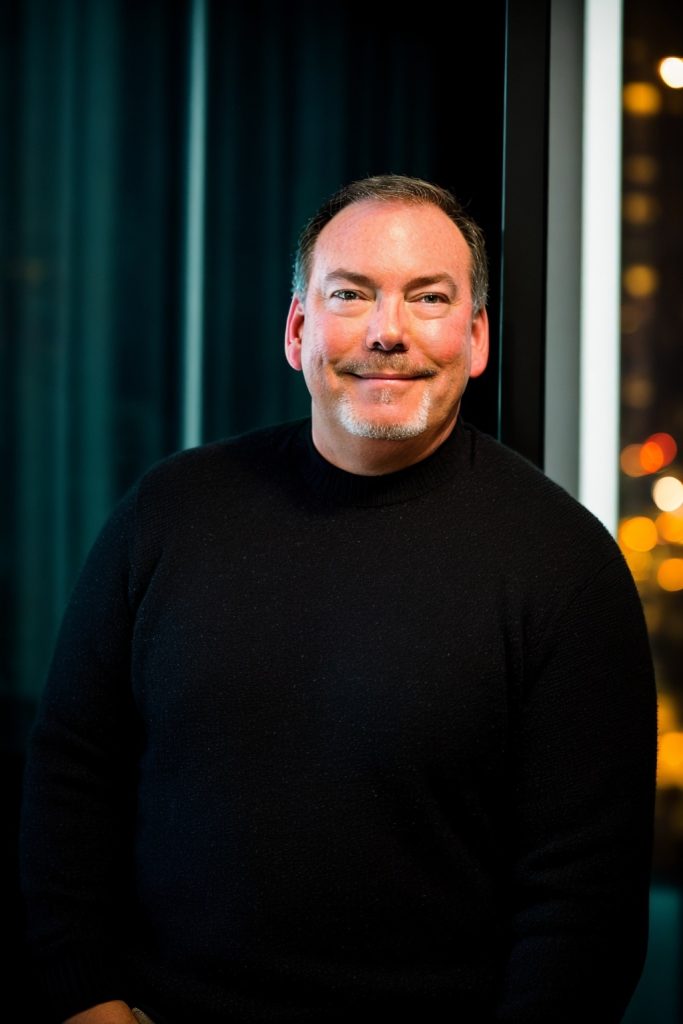 TD Smyers, CEO of BoardBuild, in a black shirt with an urban nighttime background.